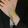 Anillo y pulsera con cadena integrada de borlas caladas europeas y americanas, pulsera de diseño único de nicho, accesorio de mano de moda resistente y exquisito
