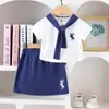 Moda Verão Gola Azul Marinho Manga Curta Top e Saia Curta Azul Marinho Estilo Academia para Meninas Casual Versátil Conjunto de Duas Peças Roupas Infantis em Estoque