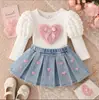 Venta al por mayor de conjuntos nuevos de primavera y otoño para niñas para exportación: Top bordado con estampado de corazones + falda vaquera plisada retro, dulce y linda