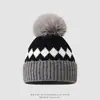 Nueva Colección Invierno 2026: Gorro Grueso de Lana Tejido Jacquard con Patrón de Diamantes en Bloques de Color y Pompones para Calidez y Protección de Orejas