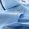 9912: Ropa de trabajo corporativa hecha a medida, incluyendo polos de manga larga con cuello de contraste, para fines de publicidad grupal; servicios de bordado proporcionados directamente por el fabricante