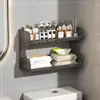 Baño de estilo abierto con un inodoro, un soporte para pañuelos de papel y toallitas húmedas encima del inodoro, y un estante de pared para toallas perfumadas