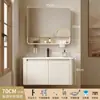 Tocador de baño engrosado y ahorrador de espacio con diseño en color crema, que cuenta con un lavabo redondeado, lavabo cerámico integrado y un lavabo de una sola pieza.