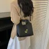 2026 Bolso de cubo de cuero suave de un solo hombro para verano, súper popular, color liso, estilo nuevo cruzado para mujer, de moda