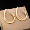 Un par de aretes grandes, geométricos, irregulares, sencillos y a la moda para mujer para el uso diario en la calle.