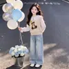 Conjunto simples e estiloso para meninas apresentando um colete fofo de urso, uma blusa doce de gola boneca estilo coreano e calças jeans versáteis com estampa de estrelas.