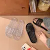 Pantuflas de gelatina cristalina de moda para mujer, con diseño hueco, drenaje completo, adecuadas para el baño, antideslizantes, de secado rápido y estilo de una tira negra.