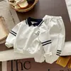 Conjunto estiloso de duas peças para bebês meninos para passeios casuais, apresentando gola e gravata contrastantes, uma blusa com estampa digital, combinada com calças de moletom listradas.