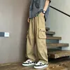 Calça cargo de perna larga estilo retrô para homens, com bolsos grandes, design moderno e minimalista, cores sólidas, caimento versátil e solto, corte reto e cintura com cordão para uso casual.