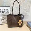 2026 Nuevo Estilo Europeo y Americano Gran Capacidad Casual Texturizado Moda Bolso Tote para Viajes Diarios Hombro Axila con Colgante de Oso para Mujer