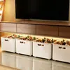 Caixa de armazenamento sob o móvel da TV, cesta suspensa para lanches e brinquedos, com rodízios para fácil movimentação, e um recipiente de armazenamento para itens diversos
