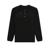 Camisa Henley negra de estilo urbano, top de manga larga con textura gofrada, sutil estampado floral y de letras, capa base casual versátil