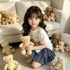 Novo Modelo de Comércio Exterior 2026 Estilo Coreano Verão Novo Conjunto de Duas Peças para Meninas com Estampa de Urso, Top de Manga Curta Dividido e Saia Plissada Xadrez