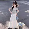 Conjunto de verão estilo universitário para menina grande: conjunto moderno de duas peças falsas com uma camiseta de cadarço e saia doce de laço
