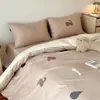 Um conjunto de quatro peças de cama com um estilo outono/inverno fresco e relaxante, apresentando tecido escovado 100% algodão de fio duplo com contagem de 50, e bordados delicados, projetado para atrair uma estética jovem e feminina.