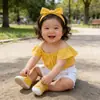 Conjunto de dos piezas de ropa infantil moderna con pantalones cortos vaqueros para niñas, top rosa con hombros descubiertos y pantalones cortos blancos.