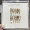 Un Diseño de Uñas Cat-Eye con Gris Champaña, Isla Dorada de los Sueños, Estilo Mil Dorados, Sonrisa Captadora de Luz, Explosión Estelar Pintada a Mano y Pedrería Apilada